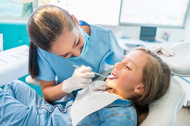 kid-dentist Beautiful girl at the dentist getting a check up on her teeth - pediatrics dental care concepts